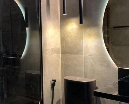 Banheiro reformado com revestimento, iluminacao indireta e metais pretos