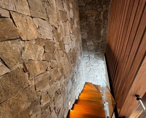 Detalhe de revestimento em pedra natural integrado a marcenaria ripada